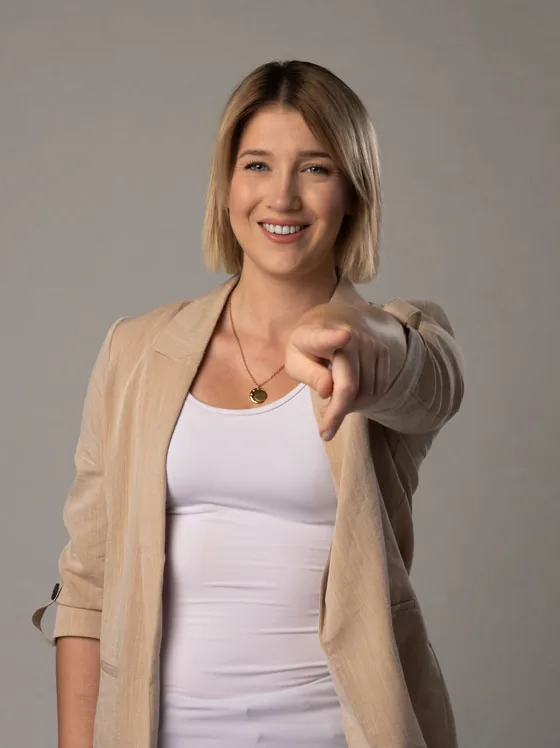 Monika zeigt l&auml;chelnd in Richtung Kamera